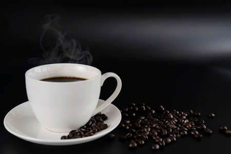 Cafes and restaurants. A mug of invigorating, black coffee and coffee beans on dark gray background. Place for an inscription. The concept of hot drinks.の写真素材