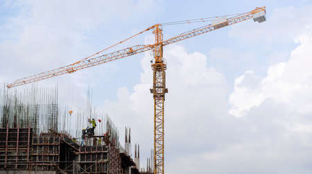 Construction site and tower crane against a blue sky withe clouds. structural steel beam build large...