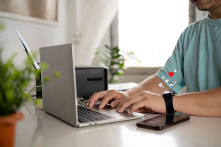 Businessmen sitting at his desk working with his laptop and smart watch alerts, messages, emails,...