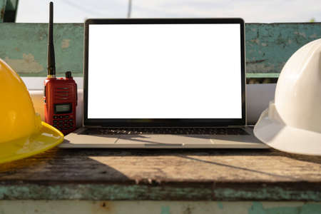 White and yellow safety helmet, laptops placed on a table in the construction area.