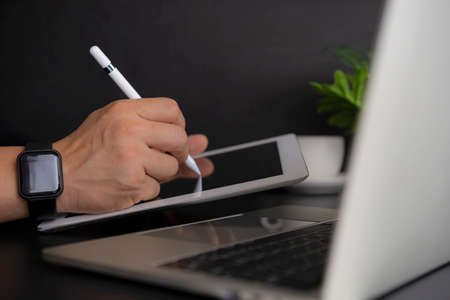 Businessman working on digital tablet and laptop computer on glass table in modern office. Business...