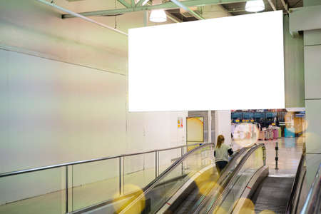 Blank large horizontal poster in public places. A mockup billboard near escalator in airport building, office building or subway station. 3D display.の写真素材