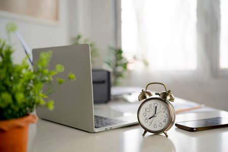 Business and finance concept of office working, Closeup clock and eyeglasses on office deskの写真素材