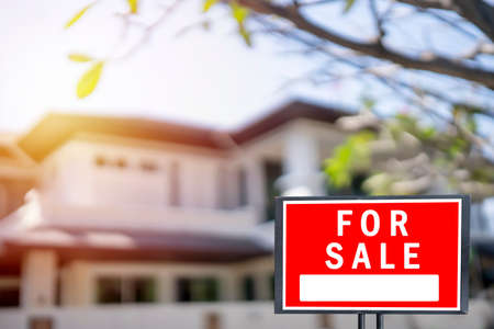 House for sale. Left facing red for sale sign outside a family houseの写真素材