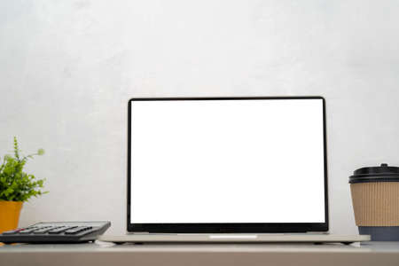 Laptop on the desk of business, coffee cup, pen, graph paper (document) on the desk (table) behind the white blind.の写真素材