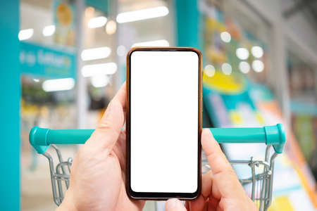 Concept nackground online shopping. Mobile phone or smartphone with cart with empty blank white...