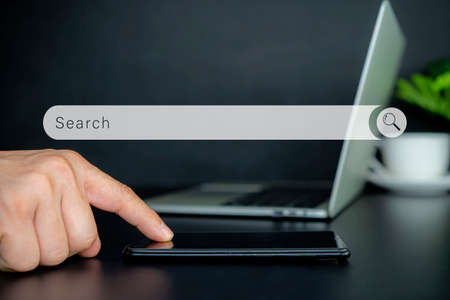 Man pointing on smartphone screen, chatting in social networks, meeting website, searching internet, sending sms, using text messenger or online banking. Close up of male handsの写真素材