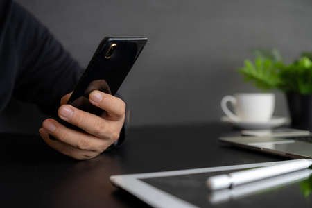 Man hold a smartphone telephone, works on the digital tablet, soft focus, close up