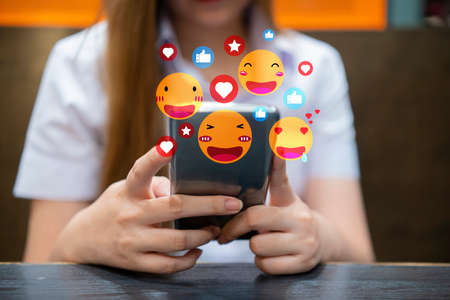 Portrait of smiling happy beauty asian woman relax use digital technology social communication with smartphone.Young asian girl look at mobile phone screen with icon online social media at cafeの写真素材