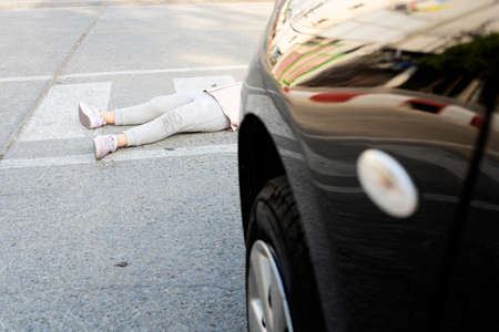 Accident. Small girl on the bicycle is hit by the car. There was a minor accident where a car hit a child at a crosswalk.の写真素材