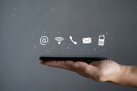 Contact us, business man hand holding a mobile smartphone with contact us icon, copy space connection concept.の写真素材