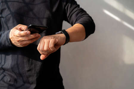 Man using smart watch and smart phone in office. New message received notification on screenの写真素材