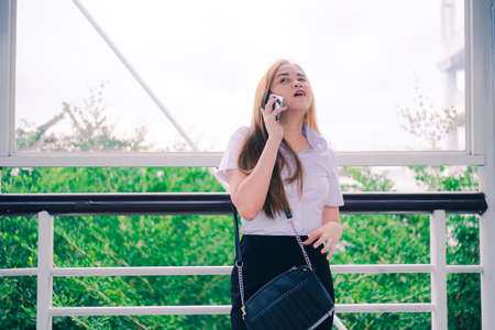 Portrait unhappy confuse young woman talking on mobile phone looking frustrated standing outdoors in garden or park. Human face expression, emotion, bad news reaction.の写真素材