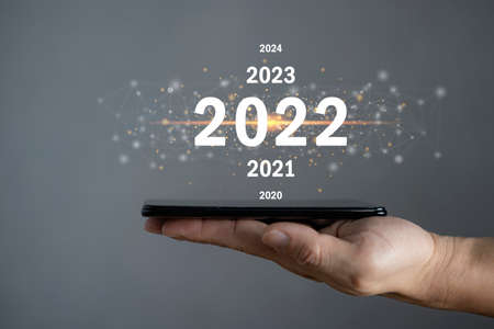 Male hand holding a smartphone and texting to change to the next year to welcome the new year 2022