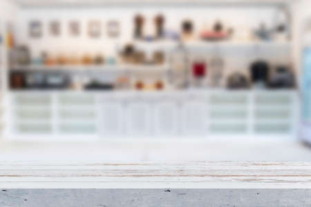 Wooden table on blurred background of kitchen window and shelves. Table top and blurred kitchen room