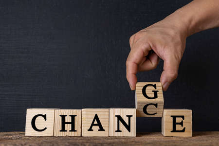 Hand flip wooden cubes that are turning words into opportunities, personal development and career growth or change yourself concepts.の写真素材