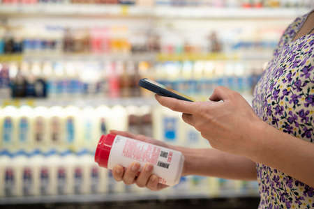 close up of asian young businesswoman is shopping for meat and scanning barcode with smart phone at supermarketの写真素材