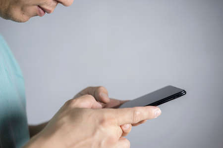 Attractive bearded businessman using smartphone while sitting on sofa at his home.Concept of young people working mobile devices.Closeup with a selected focus.Blurred background.Wideの写真素材