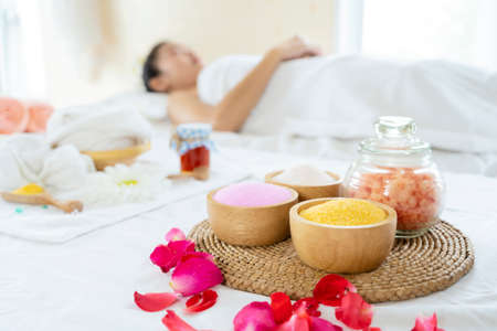 Beautiful woman having exfoliation treatment in spa. White, pink, yellow, orange bath salts on a wooden cupの写真素材