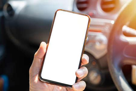 A young man drives with a phone in his hand, multitasking, no texting and driving.の写真素材