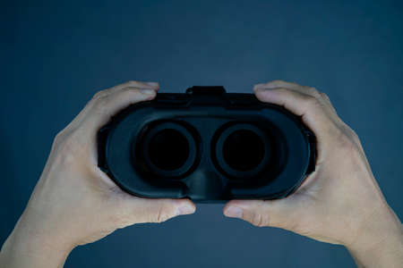 Male hands holding virtual reality, VR, gray background. Gesture about to wear VR.の写真素材