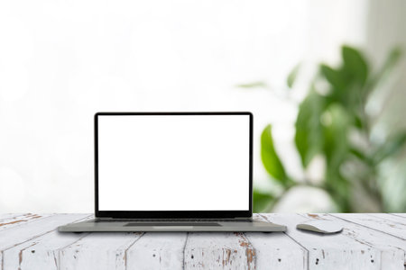 Cropped shot of simple workspace with blank screen laptop on white table with blurred office room backgroundの写真素材