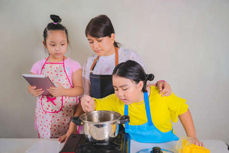 Happy loving family mother and daughter enjoying Cooking, making baked bread and bakery homemade in the kitchen at home, tease, play with baked bread, laughingの写真素材