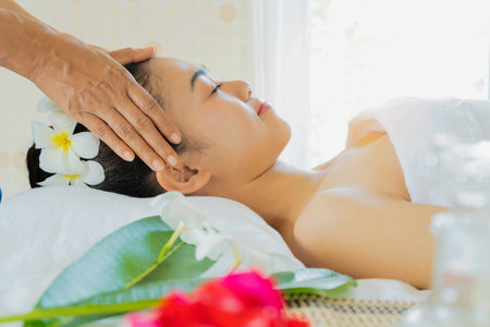 Young, beautiful and healthy woman in massaging salon. Traditional face massage therapy and skin care.の写真素材