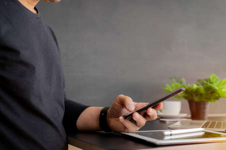 close up of a man using a smart cell phone. A happy man uses a smartphone at a stylish coffee shop, he chats online to send text messages on mobile.の写真素材