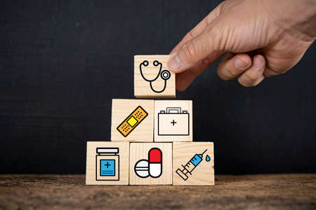 Concept of Insurance for your health. Hand hold wooden block with icon healthcare medicalの写真素材