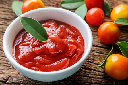 Fresh homemade tomato sauce in a white bowl, tomato sauce over wooden tableの写真素材