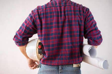 Engineer back with white helmet and holding blueprints over white isolated background.の写真素材