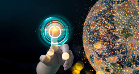Finger pressing power button energy on earth at night background. Earth day. Environment and conservation. Energy saving concept.の写真素材