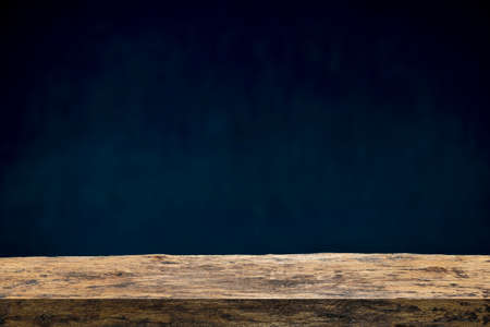 Wood table on dark background. Wooden table on black wall in dark room background for product montage.の写真素材