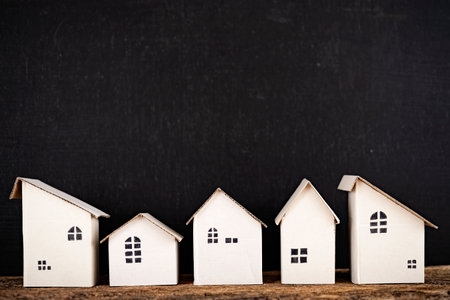 Small white houses in a row on a wooden table on a black background.の写真素材