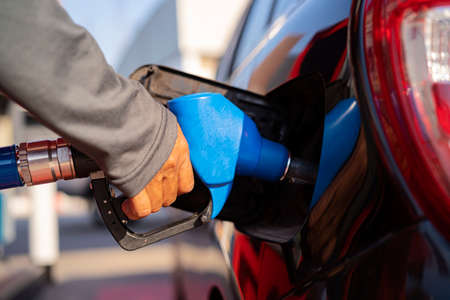 Male worker holding fuel injector refueling car tank at gas station gas station for concept transportation energy business technology conceptの写真素材