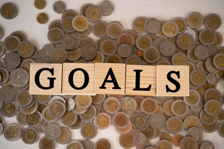 The wooden blocks are placed on piles of coins. Concept of goals, business goals to be achieved.の写真素材