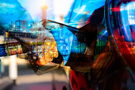 Male worker holding fuel injector refueling car tank at gas station gas station for transportation energy business technology concept. Stacked with refinery image.の写真素材