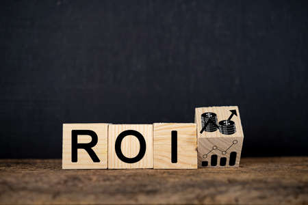 Wooden block with growth icon and "ROI" text isolated on black background. Business conceptの写真素材
