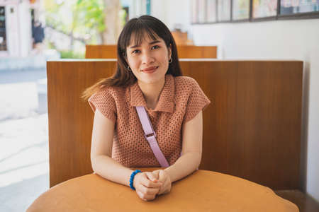 Cute pretty woman sitting in a vintage coffee shop with wooden tables.の写真素材