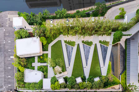 Aerial view of rooftop garden in urban residential area. Amazing park and scenic city view. Modern benches under green trees along walkway. Urban eco design and mini-ecosystem.の写真素材