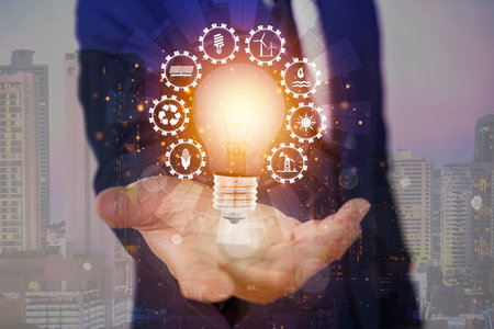 Glowing light bulb with energy resources icons in hand. Electricity and energy saving concept. Energy sources. Campaigning for ecological friendly and sustainable environment.の写真素材