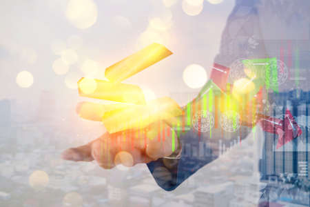 Male investor holding gold bullion with bokeh concept business and finance. World economics. Finance concept of gold between the dollar and the Euro growth chartの写真素材