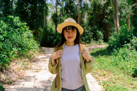 Beautiful Asia woman traveler,travel concept. woman traveler with backpack holding hat and looking at amazing mountains and forest, wanderlust travel concept, space for textの写真素材