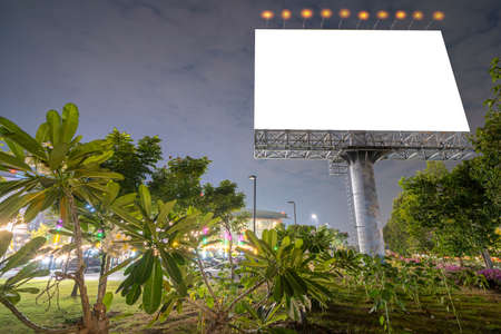 Billboard in the city street, blank screen clipping path included. There is a beautiful tree in front of the scene.の写真素材