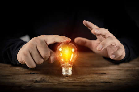 Businessman touching a bright light bulb. Concept of Ideas for presenting new ideas Great inspiration and innovation new beginning.の写真素材