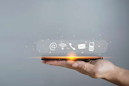 Contact us or Customer support hotline people connect. Businessman using smartphone contact icons ( email, address, live chat, internet wifi ).の写真素材