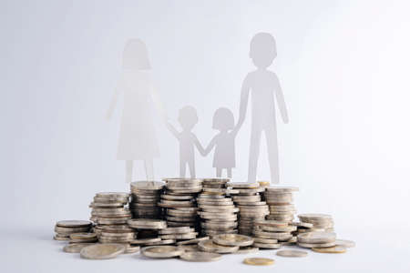 Coins stack and The paper cut of family on wood table, Nature background, Saving money for starting a married life, Building or financial stability, family planning concept.の写真素材