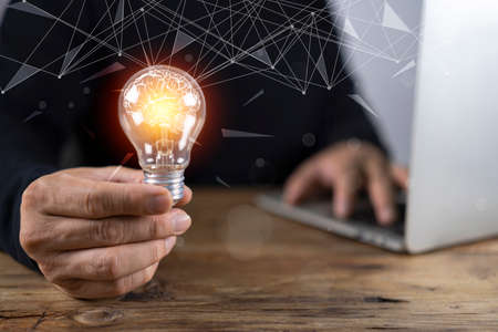 Businessman using tablet and light bulb with brain in business man's hand concept of business conceptの写真素材