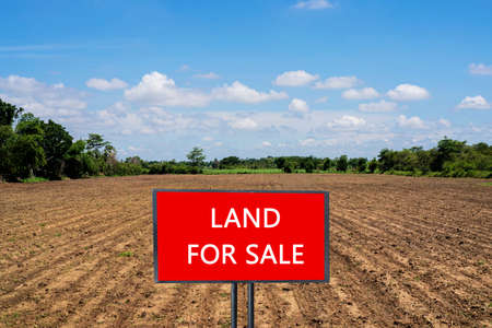 land for sale sign against trimmed lawn background. Empty dry cracked swamp reclamation soil, land plot for housing construction project in rural area and beautiful blue sky with fresh air.の写真素材